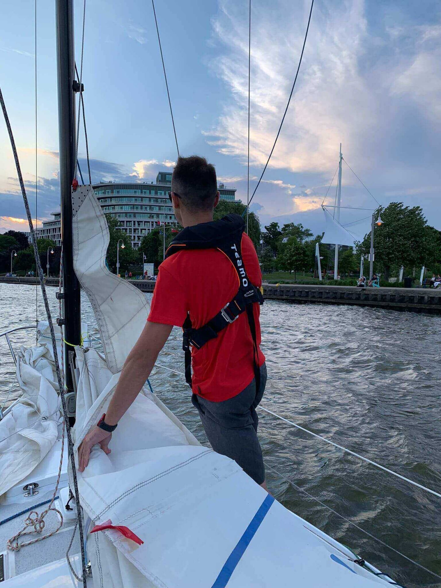 TeamO Marine Offshore Hammar PFD worn by a sailor maneuvering a sailboat in the water.