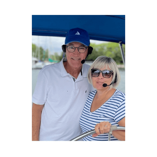 Couple wearing MESH vs 2Talk Bluetooth headsets on a boat, enjoying communication technology at sea.