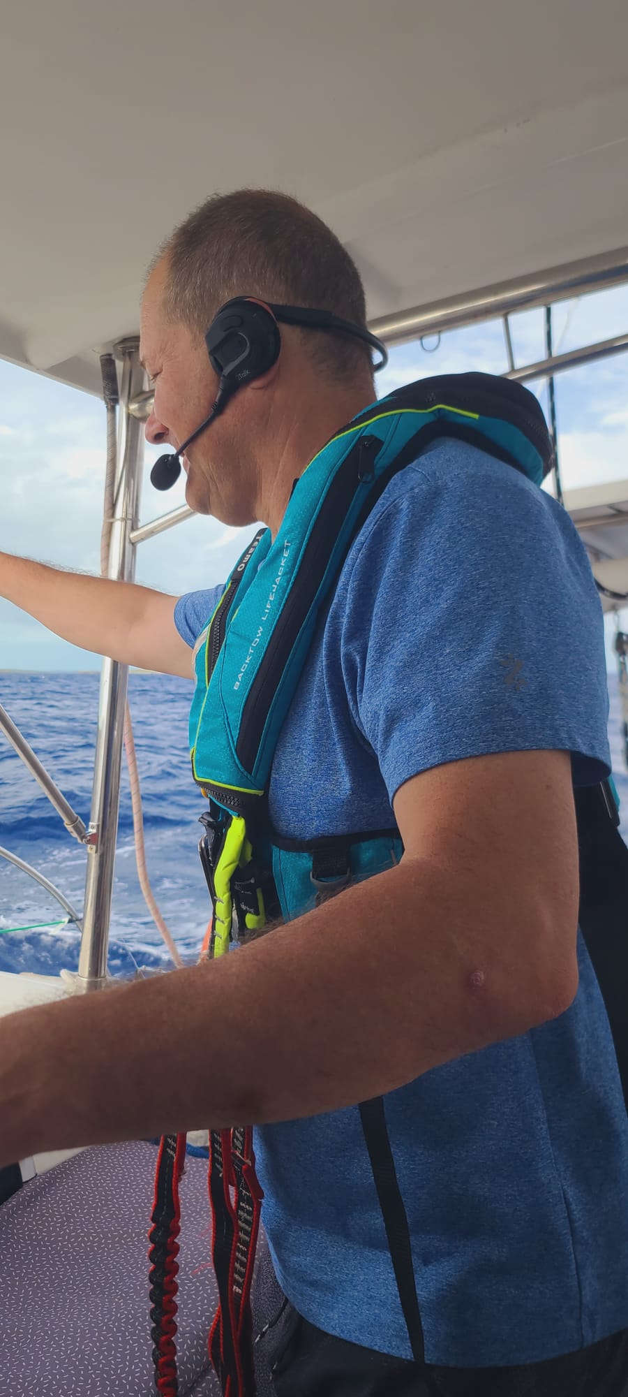 Boater wearing a 2Talk Bluetooth headset and PFD while sailing