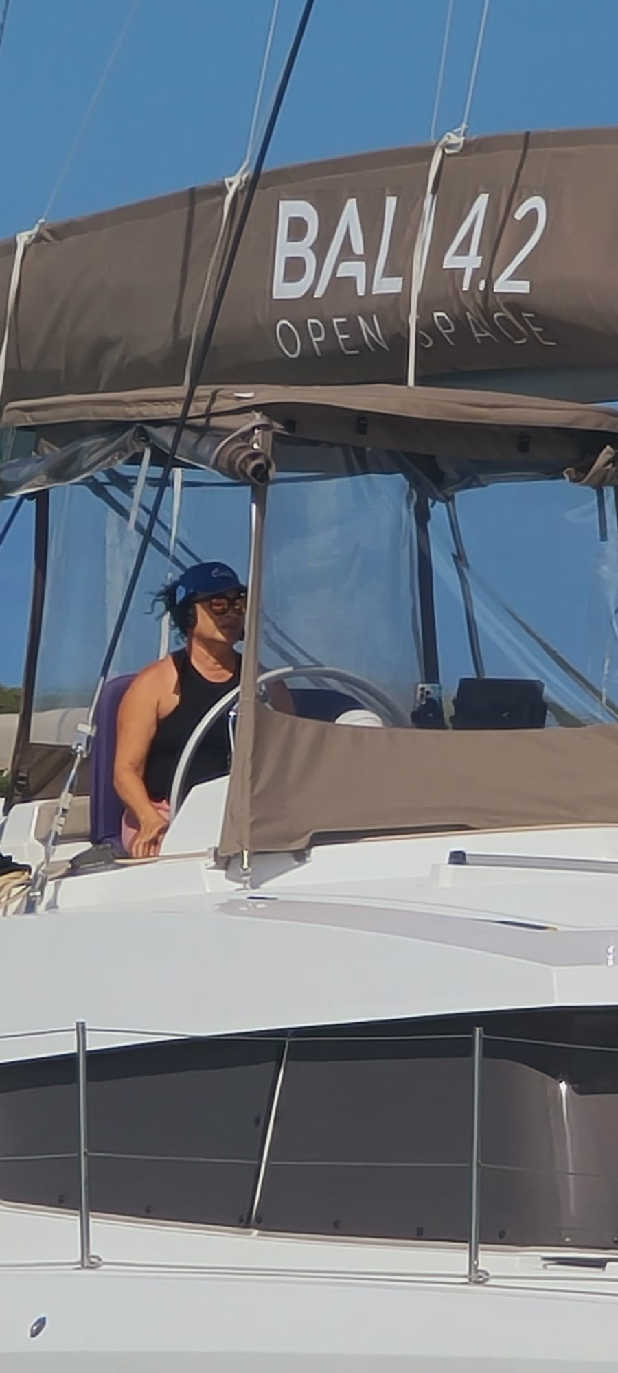 Boater wearing a 2Talk Bluetooth headset at the helm of a sailboat