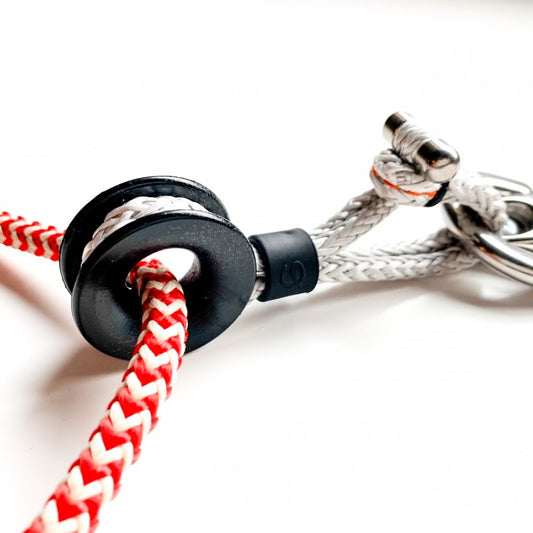 Low Friction ring with braided red and white rope and textile shackle used in sailboat rigging.
