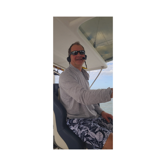 Man wearing Bluetooth headsets for boaters while steering a boat, showcasing 2Talk Marine headsets.