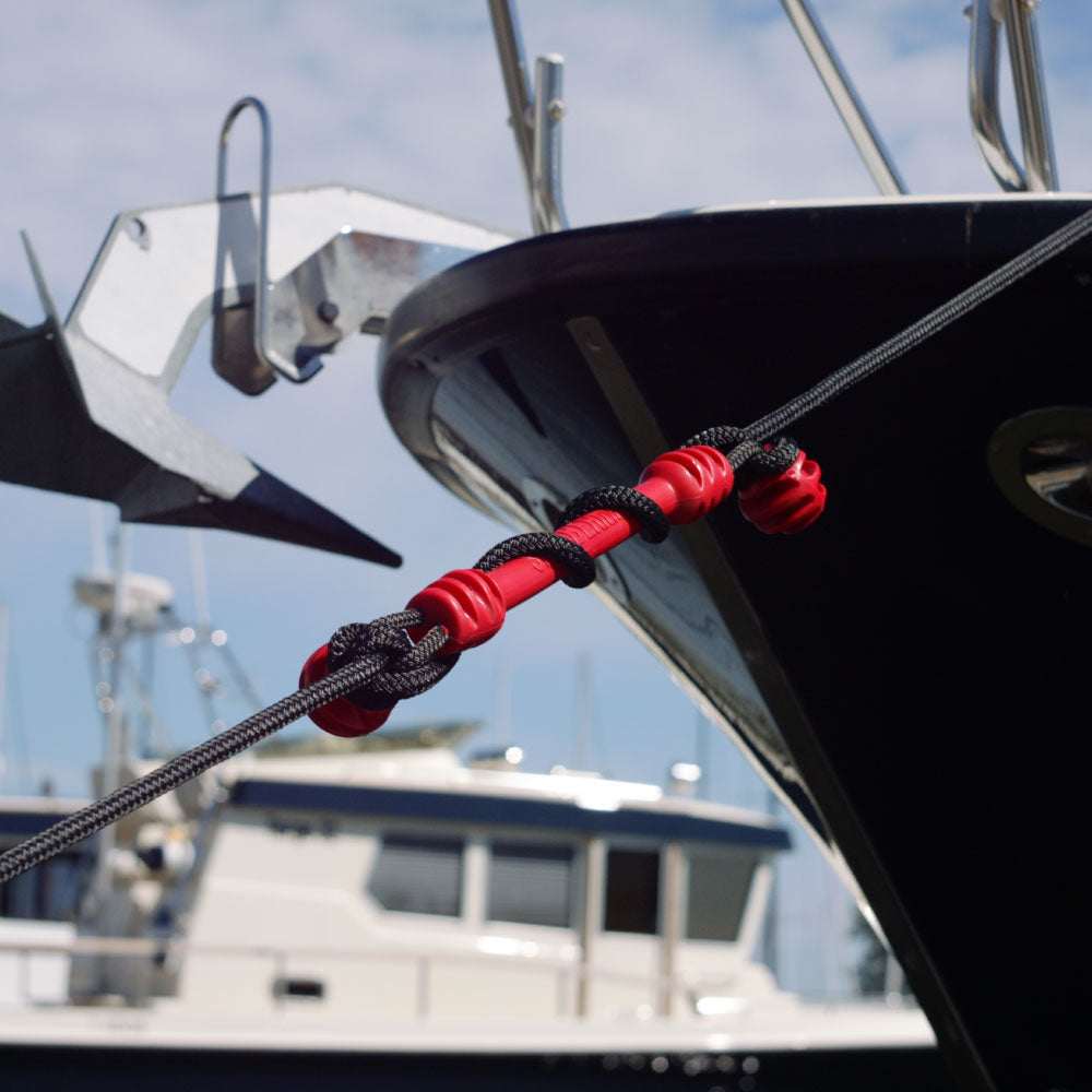 Close-up of a boat's bow with a red Snubber TWIST Single and black rope, with another boat in the background.